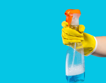 Detergent for cleaning in a female hand on blue background