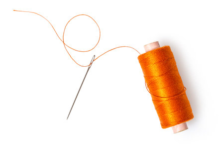spool of thread with a needle on white isolated background