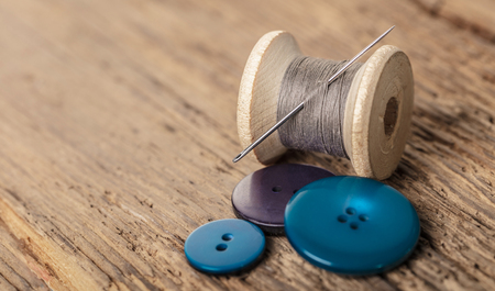 spool of threads and buttons on a wooden backgroundの写真素材