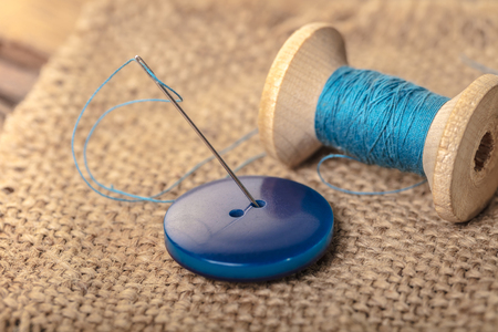 blue button with needle and thread close-upの写真素材