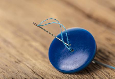 blue button with needle close-up on a wooden backgroundの写真素材