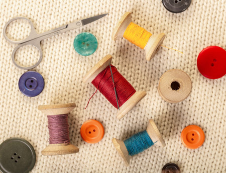 colorful threads and buttons on white knitted fabric