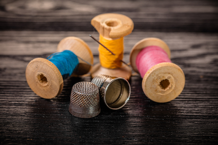 Thread and thimble on a black wooden backgroundの写真素材
