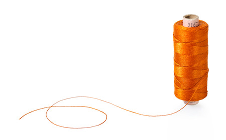 spool of orange threads on a white isolated backgroundの写真素材