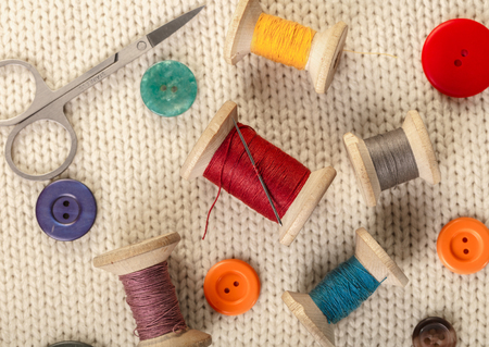 colorful threads and buttons on white knitted fabricの写真素材