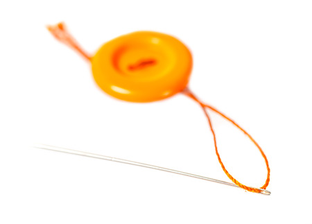 orange button with thread and needle on white isolated backgroundの写真素材