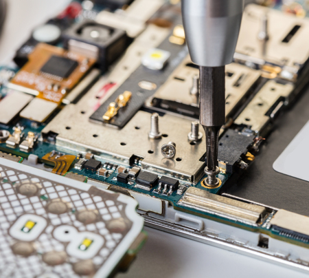 screwdriver with a screw on background of the disassembled mobile phoneの写真素材