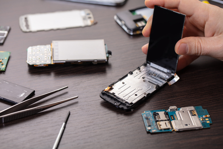 mobile phone repair, hands closeup on a wooden tableの写真素材
