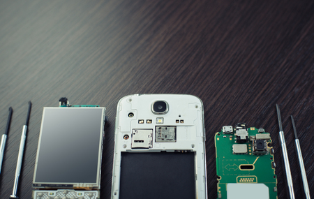 disassembled mobile phone and tools on wooden backgroundの写真素材
