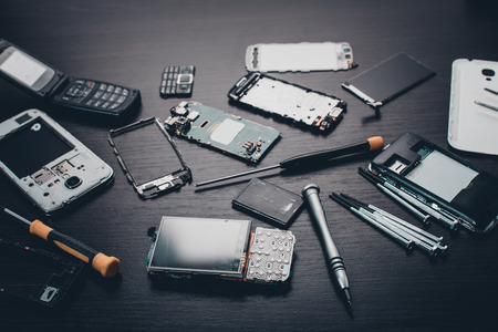 disassembled mobile phone and tools on wooden backgroundの写真素材