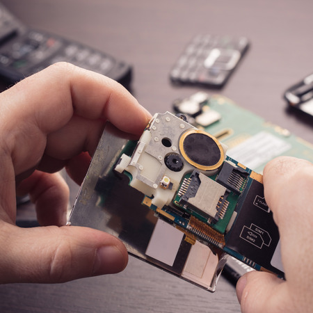 mobile phone repair, hands closeup on a wooden tableの写真素材