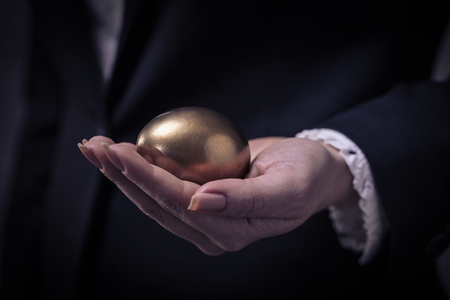 golden chicken egg in female hand closeupの写真素材