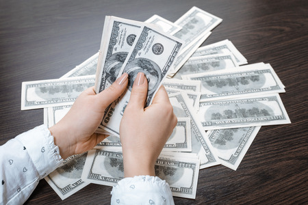 paper money in female hands on wooden backgroundの写真素材