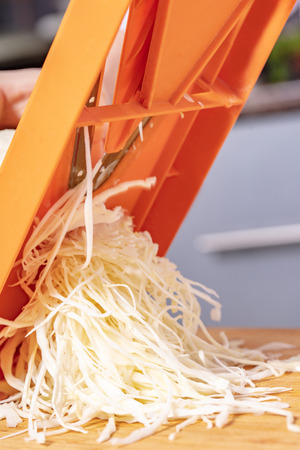 sliced cabbage on shredder, preparation for cookingの写真素材
