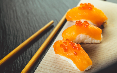 salmon sushi and chopsticks on wooden boardの写真素材
