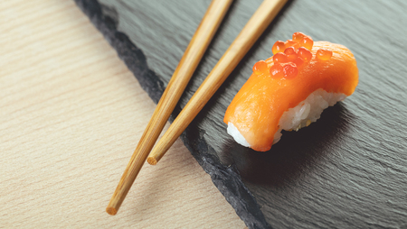 salmon sushi and chopsticks on a stone boardの写真素材