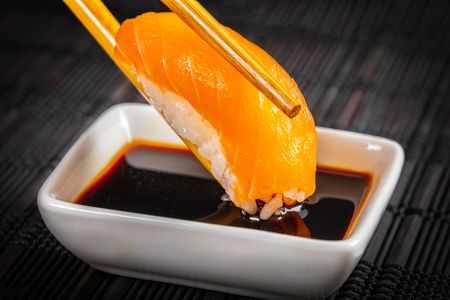 sushi dipped in soy sauce on a black backgroundの写真素材