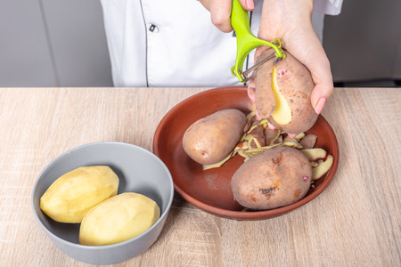 woman cook cleans potatoes, hands closeupの写真素材