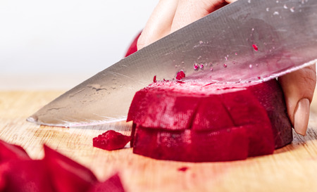 cook cuts red beet on a wooden board, preparation for cookingの写真素材