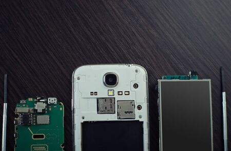 disassembled mobile phone and tools on wooden backgroundの写真素材