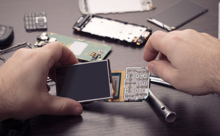 mobile phone repair, hands closeup on a wooden table