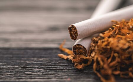 cigarettes and tobacco on a black wooden backgroundの写真素材