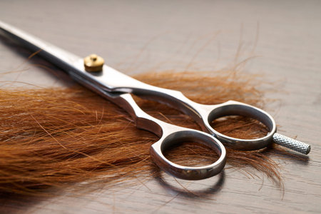scissors with a lock of hair on wooden background