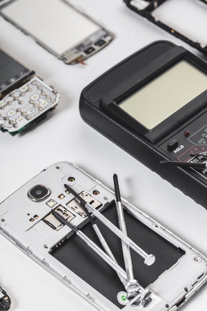 disassembled mobile phone and tools on white background