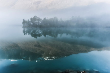 Norwegian landscape, lake with reflection of mountains in fog