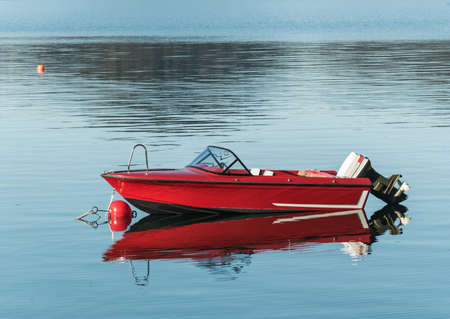 red motor boat on water with reflectionの写真素材
