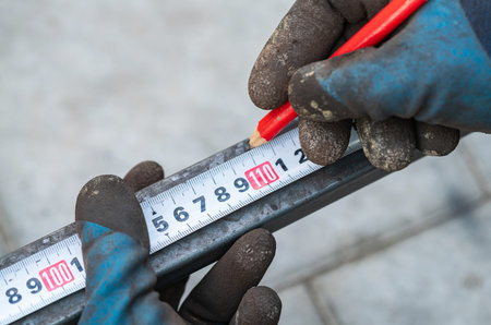 man measures metal with a ruler for cutting, hands close-upの写真素材