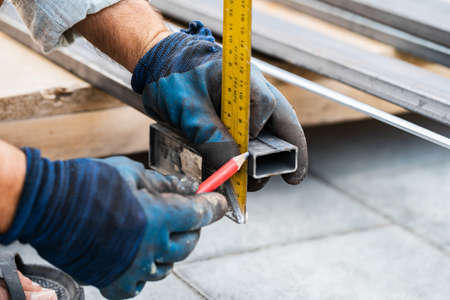 man measures metal with a ruler for cutting, hands close-upの写真素材
