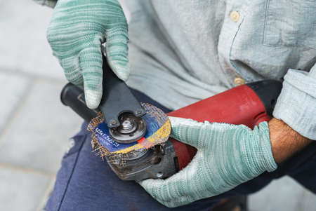 worker changes a broken blade on circular saw, hands closeupの写真素材