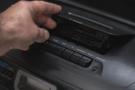 man puts a cassette in a tape recorder on a black background