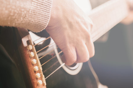 woman playing guitar, hands on strings close up