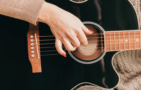 woman playing guitar, hands on strings close upの写真素材
