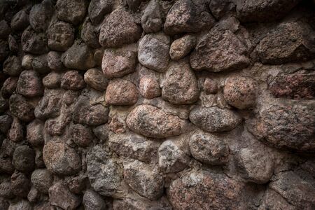 Old stone wall made up of pebbles. Pattern gray color of modern style design decorative uneven round real stone wall surface with cement. Wall design for huts made from mountain river rocks.の写真素材