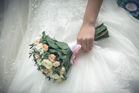 Bride is standing in forest with a bouquet in her hand showing the back of her white wedding dress and it hemline. Wedding. Detailsの写真素材