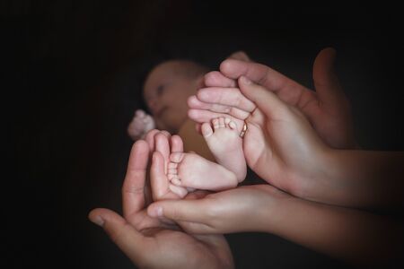 Mom and Dad hold baby legs. Taking care of a newborn.の写真素材