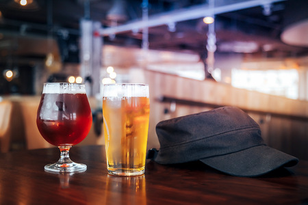 Two glasses of light and dark beer on a wooden table in a cafe or restorantの写真素材