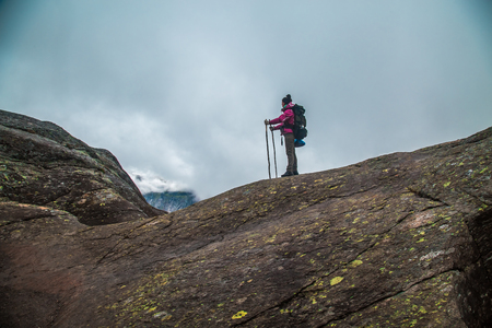 Girl stands on the peak of sandstone rock . Beautiful moment the miracle of nature. Morning mountain background. Girl watch foggy miracle.の写真素材