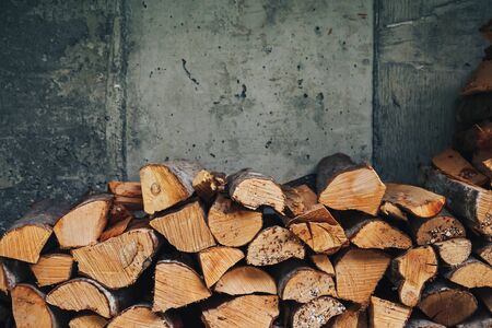 chopped logs for winter fire. Pile of firewood against old wooden fenceの写真素材