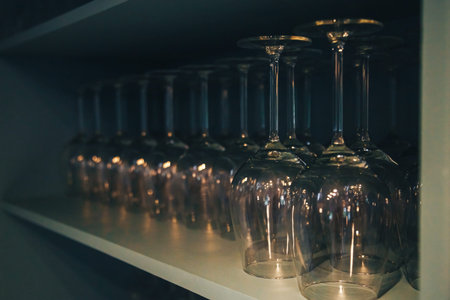 Crystal wine glasses arranged in a cupboard. Closeup of a kitchen cupboard with glass shelf and...