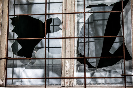 Smashed glass Window with old wooden frame on grunge wall damaged houseの写真素材