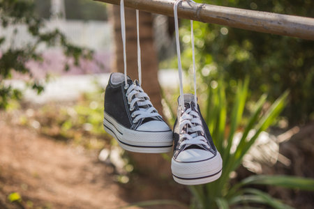 Black sneakers were dried in the sun with their shoelaces tied to a clothesline.の写真素材