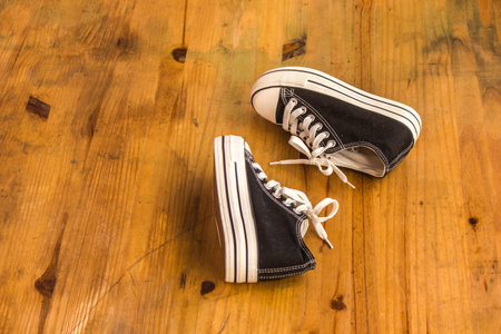 Black sneakers on the wooden floor.