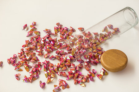 Reflective colored paper folded into a heart shape inside a jar.