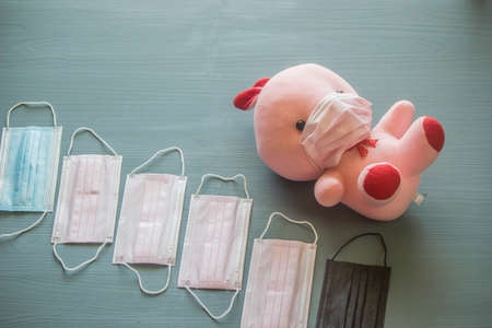 A pink doll model wearing a pink hygienic mask is placed on the floor with a number of masks placed.の写真素材