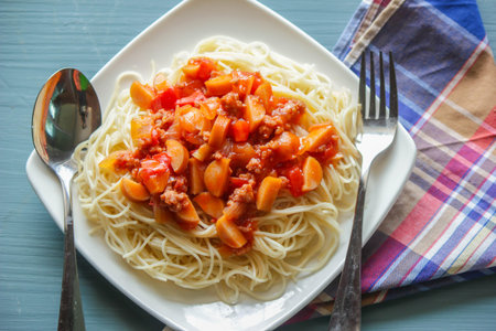 Spaghetti with ketchup scooped onto a white plate, spoons and forks are ready to serve.の写真素材