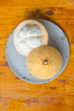 The santol fruit, cut in half, has a sour rind, sweet granules are placed in a plate.の写真素材